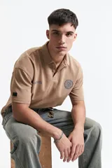 Remera polo color crema con logo bordado en el pecho, de corte amplio y mangas cortas.