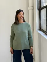 Sweater de punto color verde, de corte recto y holgado, con cuello redondo y dos bolsillos frontales aplicados.