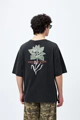 Remera negra de corte holgado con mangas cortas amplias y cuello redondo. Estampado pequeño de flor en el pecho y estampado grande en la espalda con diseño floral y texto.