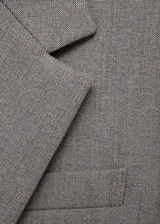 Blazer gris con solapas de muesca, cierre de un botón, dos bolsillos con solapa y un bolsillo de ribete en el pecho.