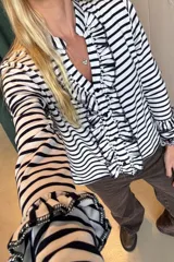 Blusa de manga larga a rayas verticales blancas y negras con volados en el frente y en el escote.