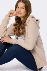 Canguro con capucha color beige, con cierre frontal y bolsillos laterales. Confeccionado en algodón y poliéster.