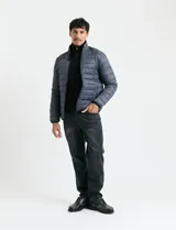 Campera acolchada tipo puffer en color gris, con cierre frontal, cuello alto y puños elásticos.