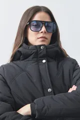 Campera puffer negra con diseño acolchado, capucha integrada y cierre frontal con botones a presión. Presenta puños elásticos y costuras decorativas en el frente.