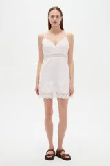 Vestido corto blanco de algodón con diseño de broderie, escote en V y tirantes finos. Presenta detalles de encaje y botones frontales.