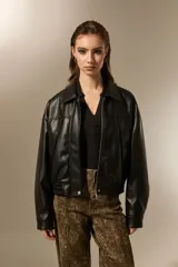 Campera de eco-cuero color negro, con cuello clásico, cierre frontal y puños con elástico. Presenta un diseño de corte holgado con costuras verticales decorativas.