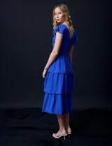 Vestido blanco de gasa con capas, marca Julia Jordan. Escote en V, manga corta con volados, corte en cintura y abertura central en espalda con cierre invisible.