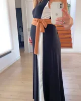 Vestido largo de corte imperio, con paneles verticales en color negro, blanco y ocre. Incluye lazo de tela ocre para ajustar debajo del busto.