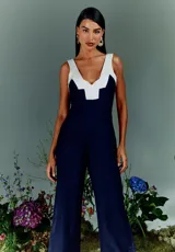 Mono largo azul marino con corte entallado, mangas tipo camiseta, cierre trasero invisible y bolsillos laterales. Presenta detalle de color blanco en la parte superior delantera y trasera.