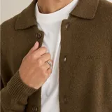 Buzo tipo cardigan de punto con botones frontales, cuello camisero y puños acanalados.