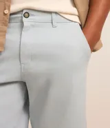Bermuda masculina slim confeccionada en sarga de algodón con elastano, con bolsillos laterales, bolsillos traseros con botón, trabillas en la cintura y cierre frontal de botón y cremallera.