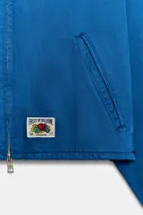 Chaqueta de cuello solapa y manga larga, de color azul, con bolsillos de vivo en los laterales, detalle de pliegues en la espalda y cierre frontal con cremallera. Cuenta con una etiqueta con logo bordado en el bajo.