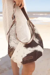 Cartera negra de cuero con forma de medialuna y tachas en zigzag.