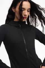 Campera deportiva de cuello alto con cierre frontal de doble cursor. Presenta un corte ajustado que realza la silueta, bolsillos laterales con cierre y mangas largas con puños con abertura para el pulgar.
