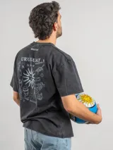 Remera de corte oversize color marrón con efecto lavado, cuello redondo y estampa frontal con la frase 'URUGUAY noma!'.