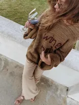 Sweater de lana merino tejido a mano, color marrón, con diseño oversize, mangas anchas y frase bordada en el frente.