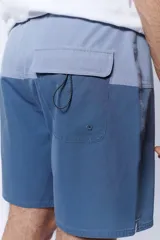 Short de baño bicolor con diseño en tonos celestes y azules, cintura elástica con cordón de ajuste gris y bolsillos laterales.