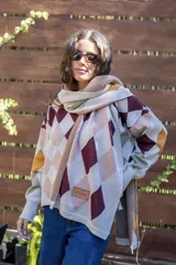 Bufanda tejida de algodón con diseño de rombos en tonos beige, bordó, rosa y mostaza. Presenta una etiqueta de cuero sintético con logo en uno de sus extremos.