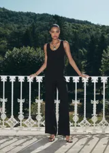 Chaleco negro de corte recto y estilo sastre, con cuello redondo abierto, tirantes anchos y cierre frontal de botones. Cuenta con forro interior completo.