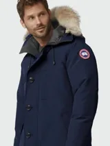 Parka azul marino de poliéster con capucha y ribete de piel, cierre con botones y logo de Canada Goose en el brazo.