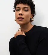 Vestido midi de punto acanalado color bordó, con cuello redondo y mangas largas. Presenta un diseño ajustado en el torso que se extiende hacia una falda con caída fluida.