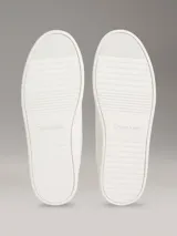 Zapatillas de perfil bajo Calvin Klein en piel color blanco, con suela cupsole de caucho y detalle de monograma grabado en el lateral.
