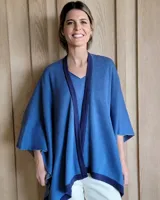 Ruana de tejido de punto en color crema con detalle de estrella grande en color verde lima en la espalda y bordes en tono arena.