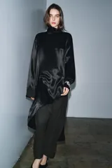 Blusa de Zara Woman Collection confeccionada en viscosa, con cuello alto, manga larga y diseño asimétrico en el bajo. Presenta un acabado satinado y cierre en la espalda.