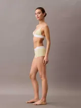Corpiño triangular de Calvin Klein, confeccionado en tejido de algodón y modal con textura acanalada. Presenta una banda elástica inferior con el logo de la marca y tirantes ajustables.