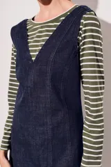 Vestido jumper corto de jean azul oscuro, con escote en V y breteles anchos.