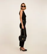 Pantalón de jeans negro, corte slim, con cintura media, trabillas en la cintura, bolsillos delanteros y traseros, y abertura en el ruedo.