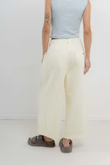 Pantalón 3/4 estilo palazzo confeccionado en denim liviano de tono amarillo pastel, tiro medio con pliegues delanteros, bolsillos delanteros y traseros aplicados, con detalle de logo metálico PEACH en la parte posterior.