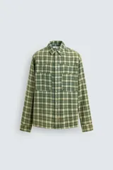 Camisa de corte relajado confeccionada en tejido de algodón con estampado de cuadros en tonos verdes y beige. Presenta cuello solapa, cierre frontal con botones a presión, bolsillos plastrón en el pecho y mangas largas con puños abotonados.