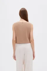 Musculosa sin mangas de color natural con cuello cuadrado y detalles de pliegues frontales en forma de chevrón.
