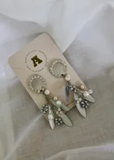 Aros colgantes plateados con base circular con strass y colgantes de hojas y perlas.