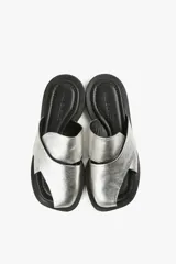 Sandalias planas de cuero color blanco hueso, con dos tiras anchas cruzadas en la parte superior y diseño minimalista.