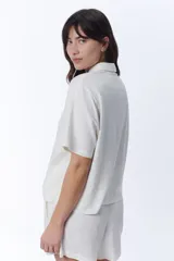 Camisa manga corta color crudo con cuello camisero y cierre frontal de botones, confeccionada con mezcla de lino.