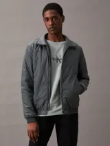 Campera bomber gris de nailon reciclado, con cuello alto, cierre de cremallera, bolsillos laterales y puños y bajo elásticos.