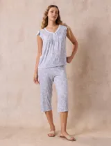 Conjunto de pijama marca René Rofé, compuesto por una remera de escote en V con botones y un pantalón capri con cintura elastizada, ambos en tejido soft estampado con motivos florales en tonos celeste y blanco.