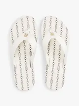 Ojotas blancas con tiras de tejido trenzado y una pequeña insignia con el monograma TH a contraste en la tira del dedo. La suela es de EVA con una línea decorativa azul marino en el borde.