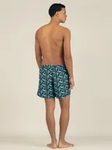Short de baño con estampado floral pixelado en tonos azul, celeste y negro. Cuenta con cintura elástica ajustable, dos bolsillos laterales y un bolsillo trasero con cierre.