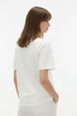 Remera de manga corta color blanco, de corte holgado con cuello redondo a la base y estampado frontal en tono bordó de un gato y un ovni en un paisaje desértico.