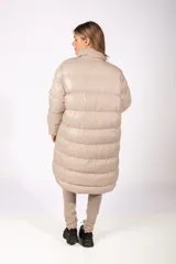 Campera puffer larga de color negro con acabado brillante, cierre frontal con botones a presión y cuello alto. Presenta un parche circular en la manga izquierda.