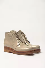 Bota acordonada de cuero vacuno con acabado charol color suela, con suela de goma tipo crepe y costuras reforzadas.