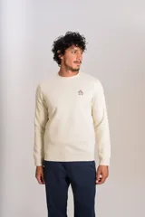 Buzo de cuello redondo color crudo, con detalle de logo bordado en el pecho, mangas largas y puños elastizados.