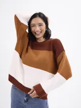 Buzo de tejido de punto con diseño de bloques horizontales en tres colores: marrón oscuro, marrón claro y blanco. Presenta cuello redondo y mangas largas con calce relajado.