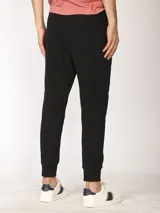 Pantalón de jogging color verde militar, corte slim, con puños elastizados en los tobillos y cordón ajustable en la cintura. Presenta un bolsillo lateral con cierre.