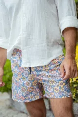 Short de baño con estampado de flores en tonos pastel sobre fondo celeste.