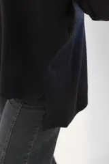 Sweater de punto color negro con cuello alto y diseño de rombos en relieve. Presenta mangas largas con puños acanalados y un corte holgado con aberturas laterales en el ruedo.