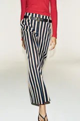 Pantalón de tiro alto y pernera recta con estampado de rayas verticales en tonos azul, marrón y beige. Incluye un cinturón delgado de color marrón oscuro con hebilla metálica dorada.